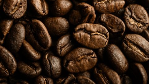 Close-up of high-quality Coffea canephora beans next to Arabica beans on a wooden table