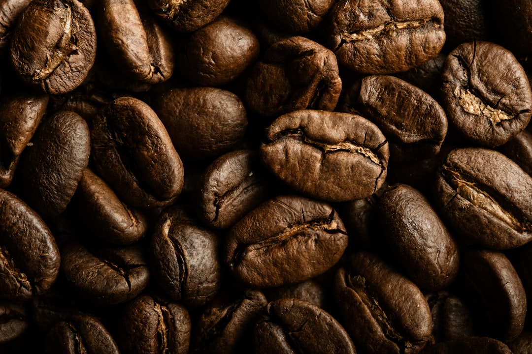 Close-up of high-quality Coffea canephora beans next to Arabica beans on a wooden table
