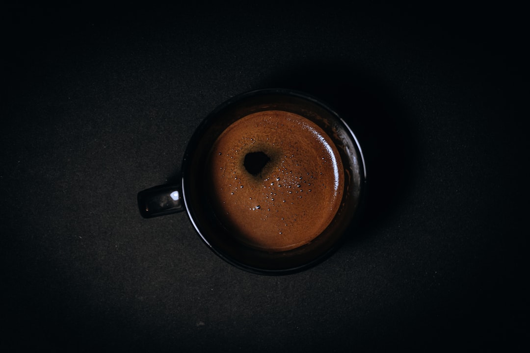 A dark, rich cup of kissaten coffee culture served in a traditional ceramic cup with a metal filter nearby.