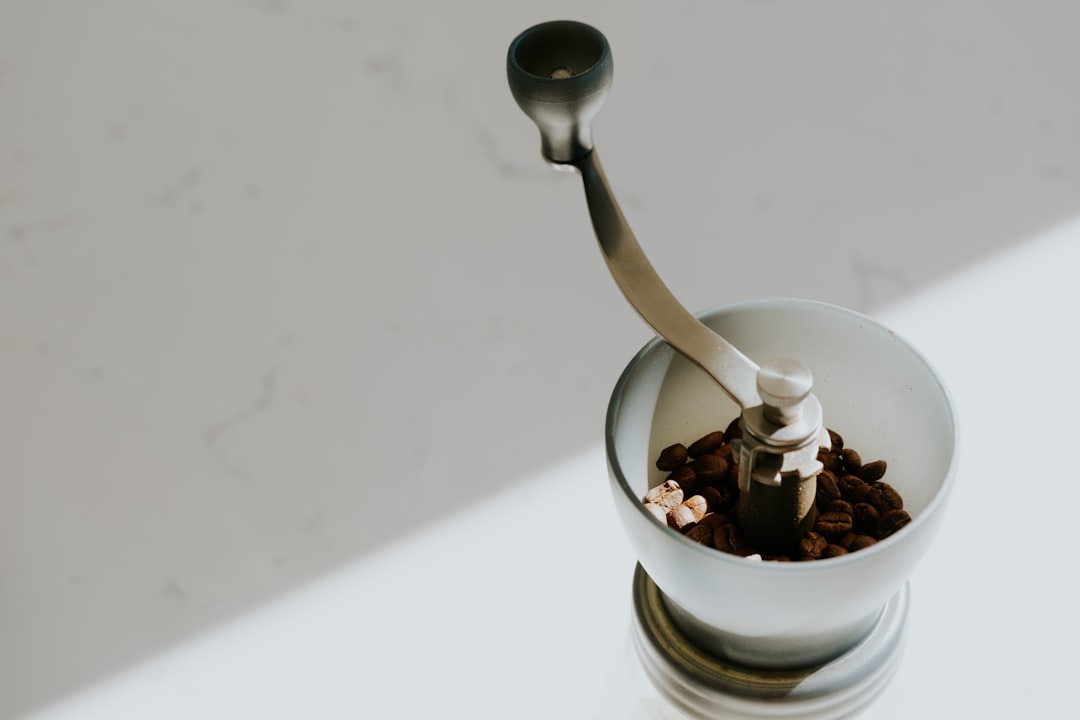 A close-up of a broken built-in espresso grinder mechanism with scattered coffee grounds